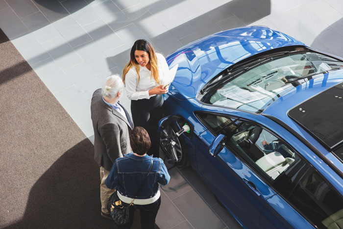 Bilförsäljare säljer en ny fräsch blå bil till ett par